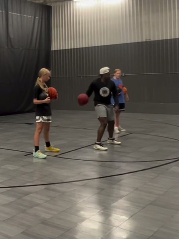 Coach Darrel Wilson running a ball handling warm-up with two athletes